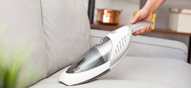 Cleaning sofa with portable vacuum cleaner