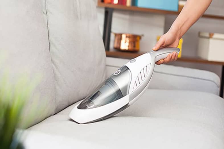 Cleaning sofa with portable vacuum cleaner
