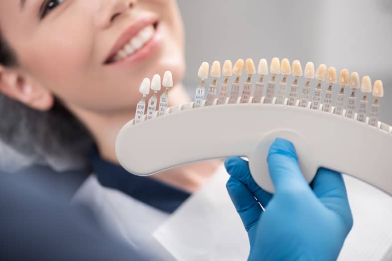 Odontologist arms showing teeth implants to patient
