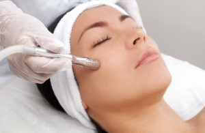 The cosmetologist makes the procedure Microdermabrasion of the facial skin of a beautiful, young woman in a beauty salon.Cosmetology and professional skin care.