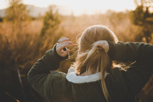 Girl tying her honey blond hair