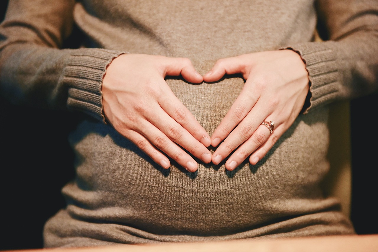 Pregnant woman forming a heart shape with her hands on her belly